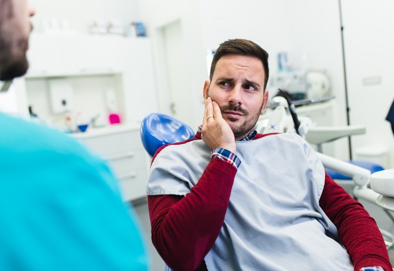 Dentist in Trenton, MI explaining dental care to patient with tooth discomfort